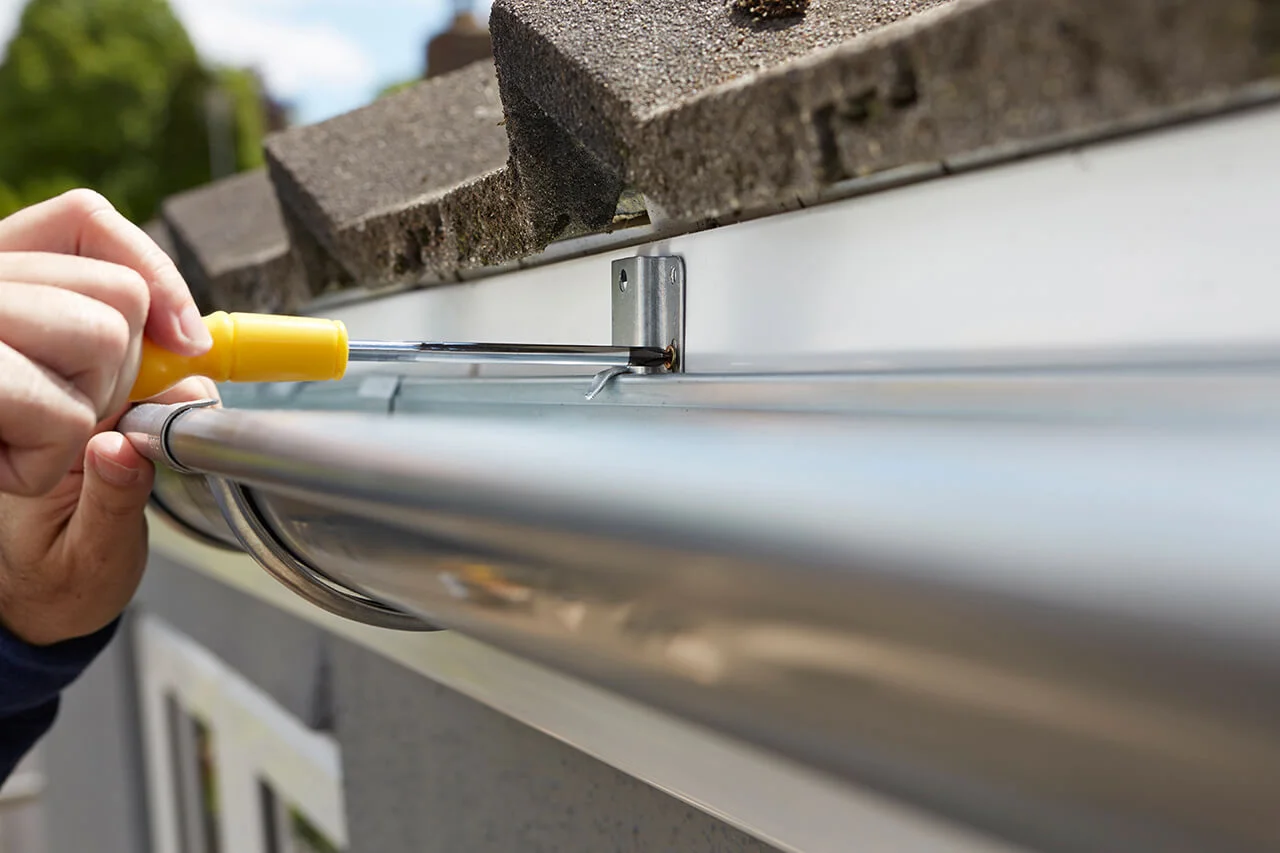 Technician repairing gutter with screwdriver